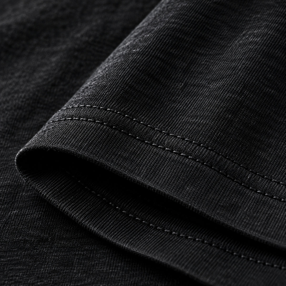 Close-up of black shirt fabric and double-needle sleeve hem stitching.