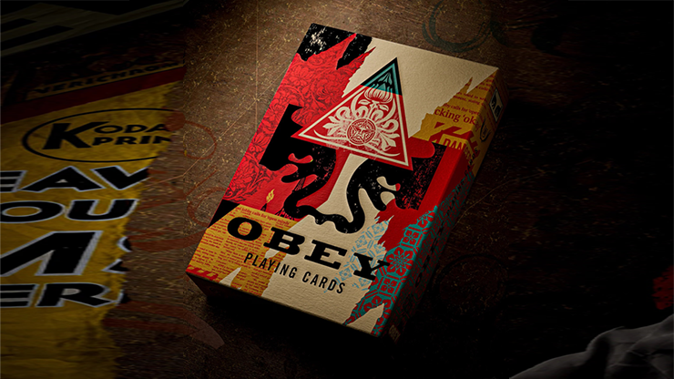 Obey Collage Edition playing cards by theory11 tuck case featuring Shepard Fairey collage artwork displayed on a dark tabletop background
