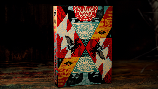 Obey Collage Edition playing cards by theory11 tuck case featuring Shepard Fairey collage artwork displayed on a dark tabletop background