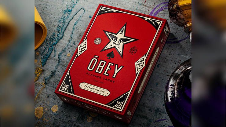 Obey Red Edition playing cards by theory11 premium tuck case box with star emblem and bold red design displayed on an art studio table