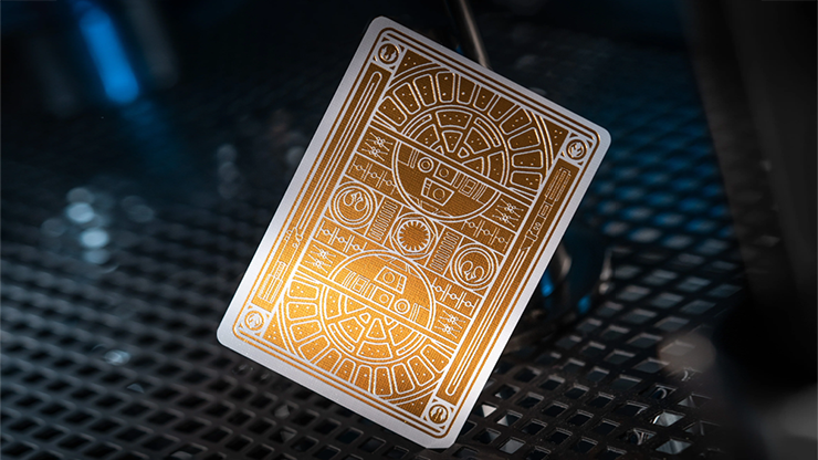 Gold foil back design from Star Wars playing cards by theory11 resting on a dark metal surface with cinematic lighting
